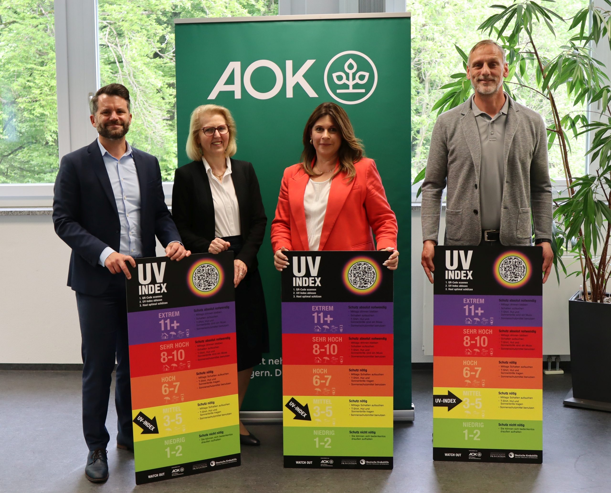 Bild mit vier Personen, die die Kampagne für mehr Sonnenschutz und Hautkrebsprävention bewerben